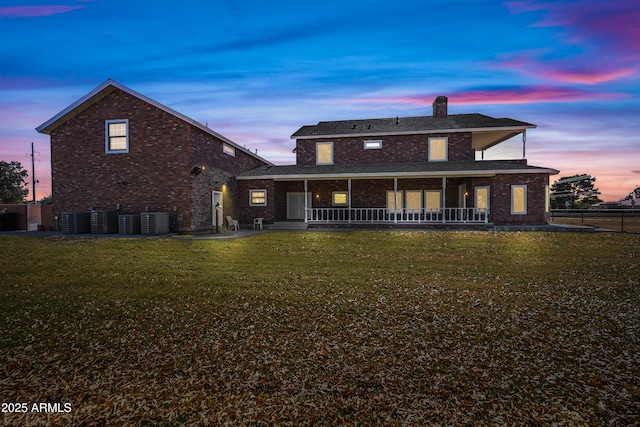 back house at dusk featuring a lawn, central air condition unit, and a porch