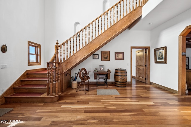 stairway featuring a high ceiling and wood-type flooring