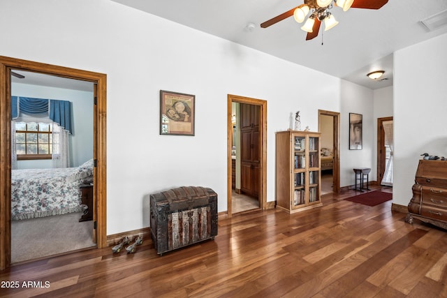 living area featuring ceiling fan and dark wood-type flooring