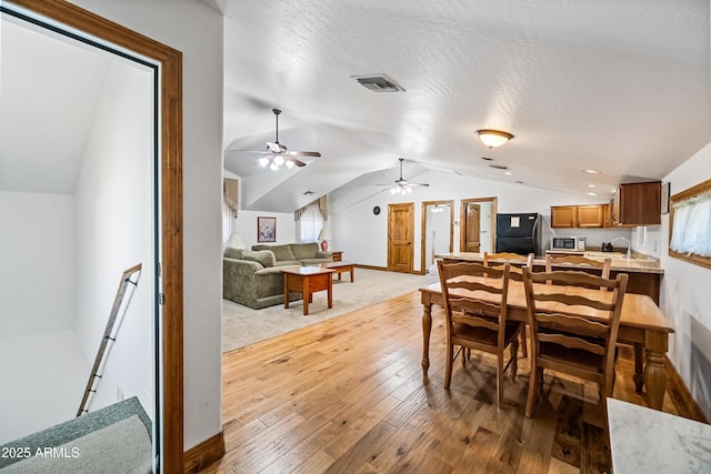 dining area featuring ceiling fan, vaulted ceiling, a textured ceiling, and hardwood / wood-style flooring