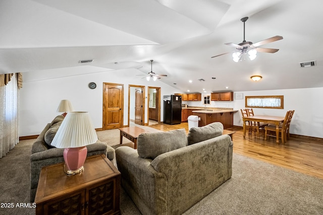 living room with vaulted ceiling, ceiling fan, and light hardwood / wood-style floors