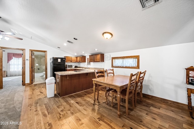 dining space featuring ceiling fan, light hardwood / wood-style flooring, and vaulted ceiling