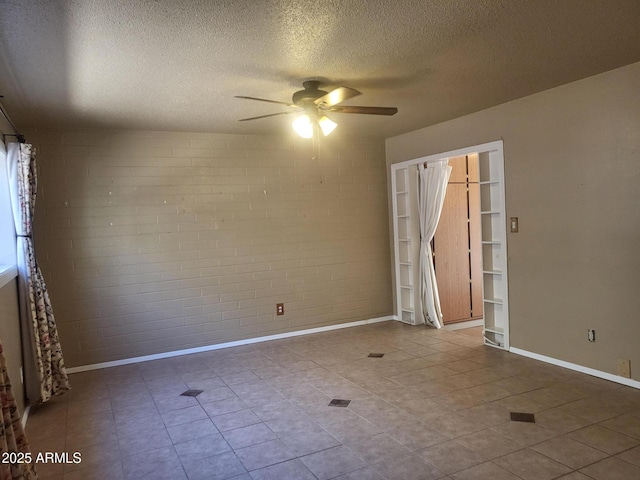 720 N 82nd St Unit E116, Scottsdale, AZ 85257 - tiled empty room featuring a ceiling fan, a textured ceiling, baseboards, and brick wall