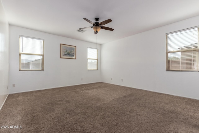 carpeted spare room with a ceiling fan and visible vents