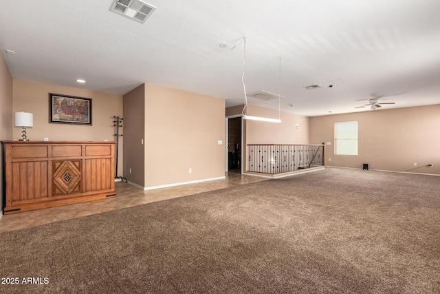 spare room featuring light carpet, ceiling fan, visible vents, and baseboards