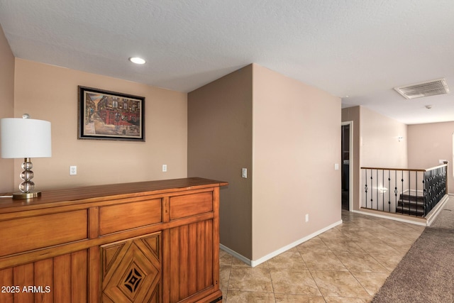 hallway with light tile patterned floors, baseboards, and visible vents