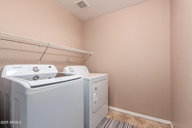 laundry area with laundry area, baseboards, visible vents, washer and dryer, and light tile patterned flooring