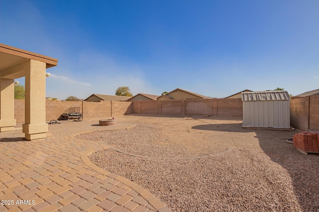 view of yard with a patio area, a fenced backyard, a storage unit, and an outbuilding