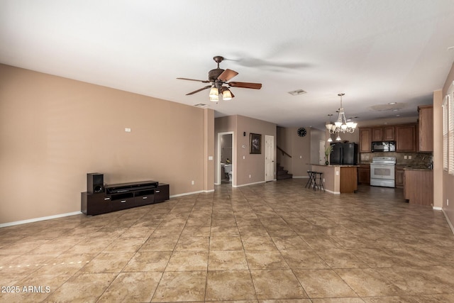 unfurnished living room featuring ceiling fan with notable chandelier, a sink, visible vents, baseboards, and stairway