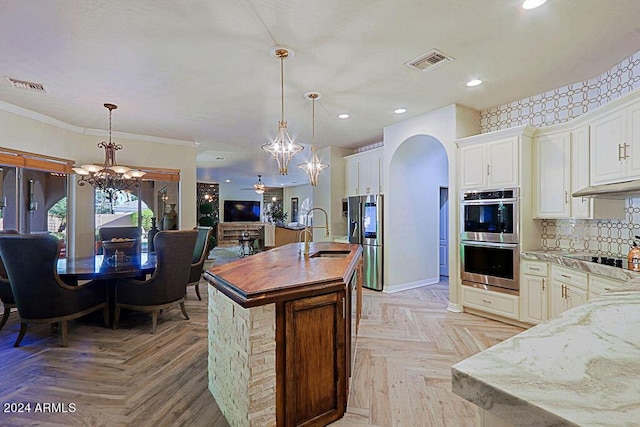 kitchen with sink, light stone counters, pendant lighting, and appliances with stainless steel finishes