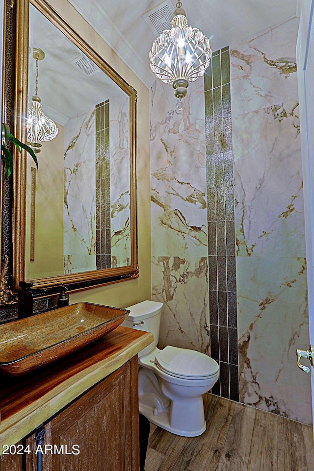 bathroom with hardwood / wood-style flooring, toilet, vanity, ornamental molding, and a chandelier