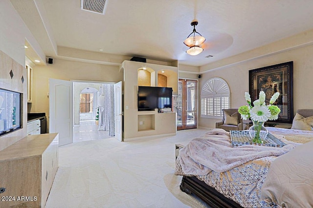 bedroom with light carpet, ensuite bathroom, and french doors