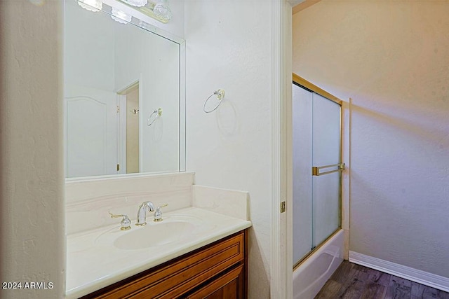 bathroom featuring shower / bath combination with glass door, hardwood / wood-style flooring, and vanity