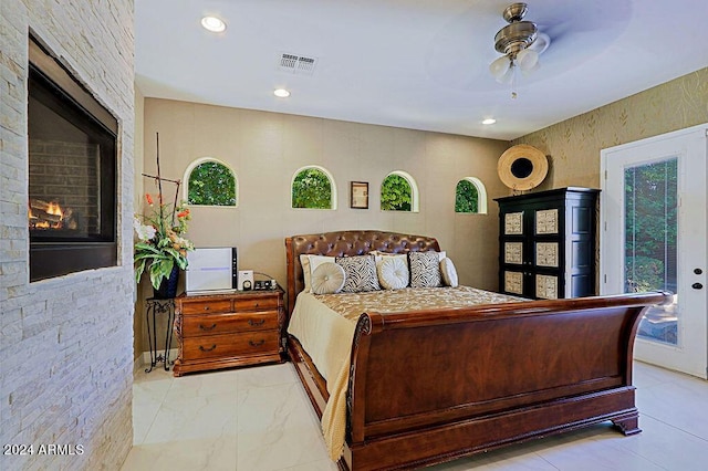 bedroom with ceiling fan, access to exterior, and a large fireplace