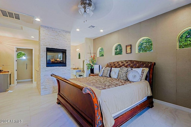 bedroom with ceiling fan and a stone fireplace