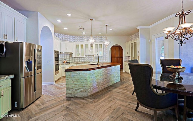 kitchen featuring appliances with stainless steel finishes, wood counters, white cabinetry, sink, and hanging light fixtures