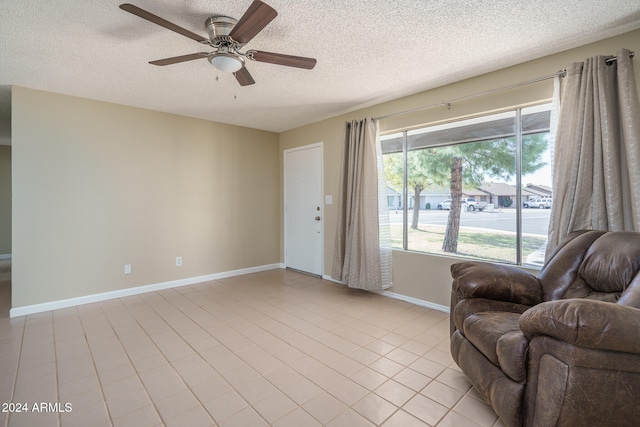 sitting room with ceiling fan, light tile patterned floors, and a textured ceiling