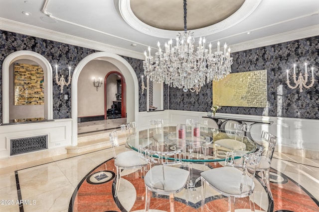 dining room featuring wallpapered walls, ornamental molding, a raised ceiling, and a wainscoted wall