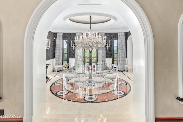 dining space featuring a chandelier, arched walkways, a raised ceiling, and ornamental molding