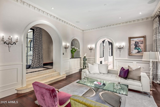 living room featuring a wainscoted wall, arched walkways, a decorative wall, and dark wood-type flooring