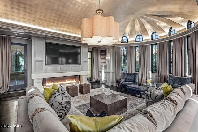 living area with lofted ceiling, a warm lit fireplace, and wood finished floors