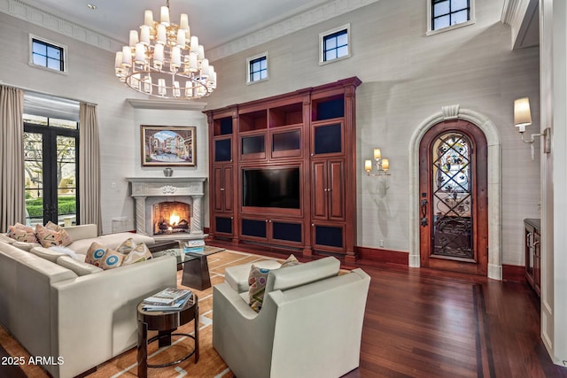 living room with a warm lit fireplace, french doors, dark wood-type flooring, and a healthy amount of sunlight