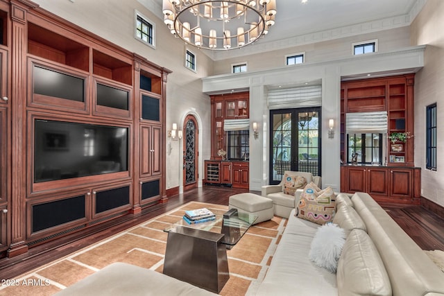 living room featuring dark wood-style floors, baseboards, a towering ceiling, and a notable chandelier