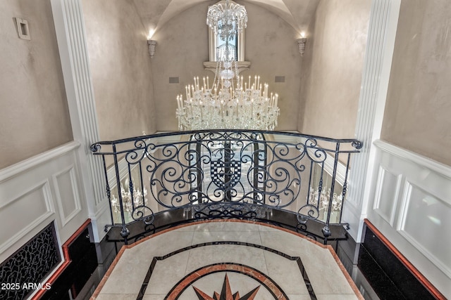 stairs with a chandelier, wainscoting, and a decorative wall