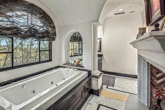 bathroom with a jetted tub, marble finish floor, a fireplace, and baseboards