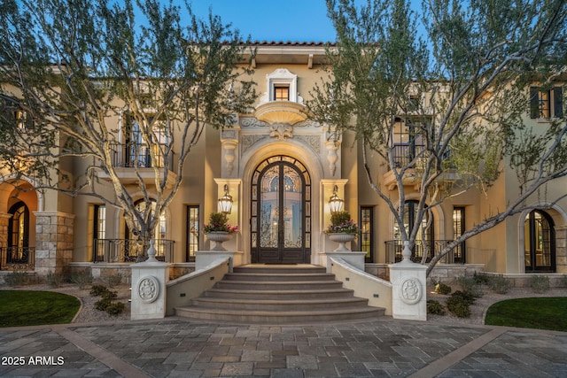 entrance to property featuring french doors and stucco siding