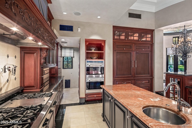 kitchen featuring light tile patterned floors, visible vents, double oven, glass insert cabinets, and a sink