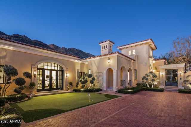 view of front of property featuring stucco siding, a tile roof, a mountain view, and french doors