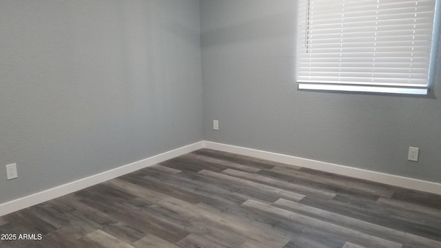unfurnished room with dark wood-type flooring and baseboards