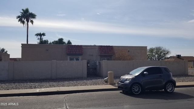 view of front of house featuring a tile roof, uncovered parking, and stucco siding