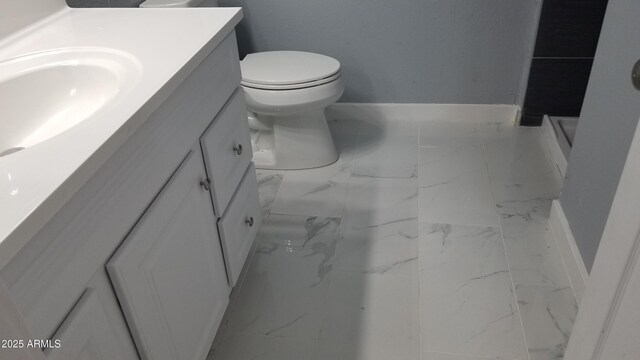 bathroom featuring marble look tiles, vanity, baseboards, and toilet