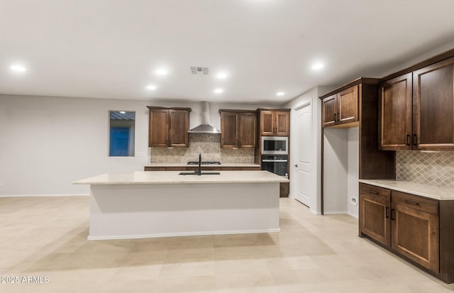 kitchen with visible vents, wall chimney exhaust hood, dark brown cabinetry, stainless steel microwave, and backsplash