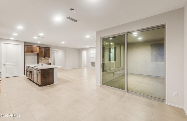 kitchen featuring recessed lighting, light countertops, visible vents, arched walkways, and a sink