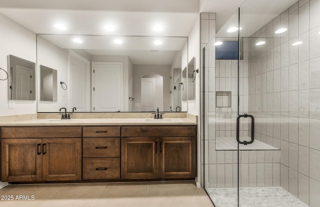 full bath featuring a stall shower, double vanity, a sink, and tile patterned flooring