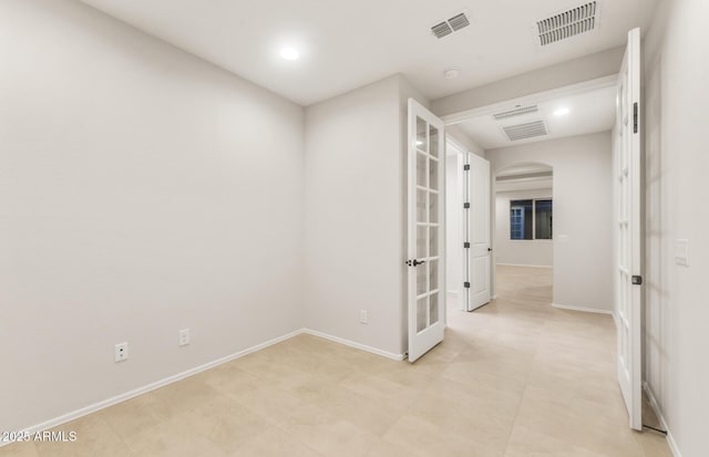 empty room featuring visible vents, baseboards, and arched walkways