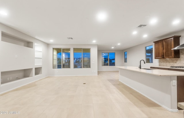 kitchen featuring a kitchen island with sink, a sink, visible vents, and stainless steel gas stovetop