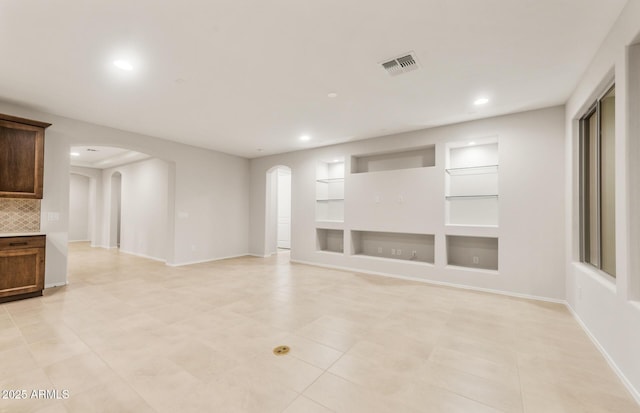 unfurnished living room with recessed lighting, arched walkways, and visible vents