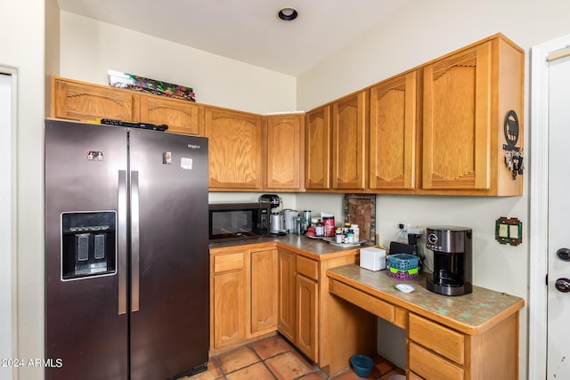 kitchen featuring stainless steel fridge, built in study area, black microwave, dark countertops, and brown cabinets