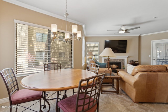 dining room featuring crown molding, ceiling fan, a chandelier, a tile fireplace, and light tile patterned floors