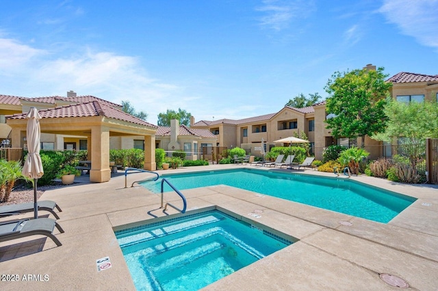 community pool with a hot tub, fence, and a patio area