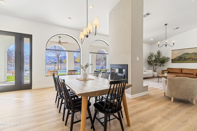 dining area with light hardwood / wood-style floors, a notable chandelier, and a large fireplace