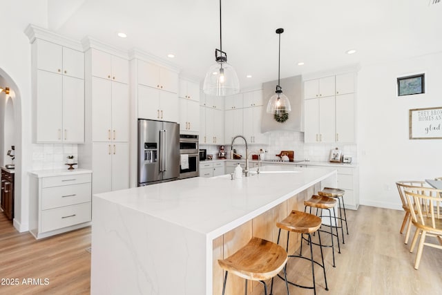 kitchen featuring light hardwood / wood-style floors, white cabinetry, a kitchen island with sink, and appliances with stainless steel finishes