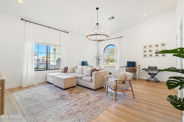 living room featuring light hardwood / wood-style floors, a chandelier, and vaulted ceiling