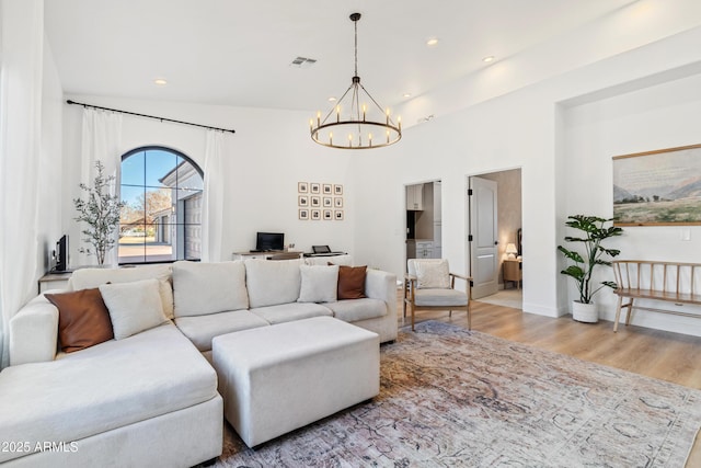 living room with light hardwood / wood-style floors, vaulted ceiling, and an inviting chandelier