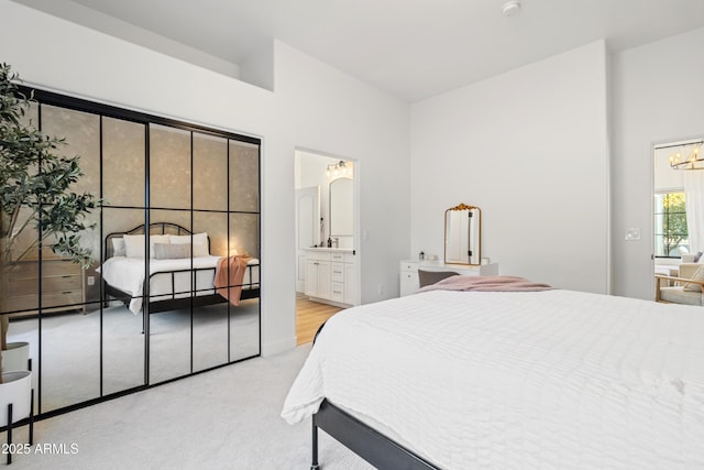 bedroom with an inviting chandelier, light colored carpet, and ensuite bathroom