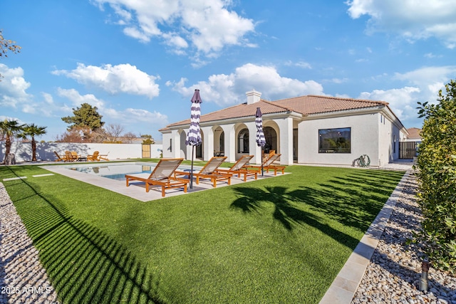 rear view of house featuring a fenced in pool, a patio area, and a yard